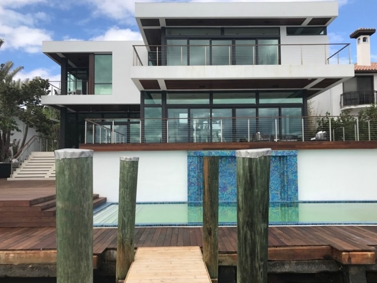 Modern waterfront home with impact windows and glass railings
